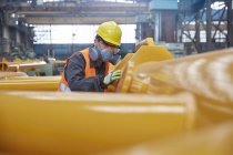 Stahlarbeiter mit Mundschutz, der Ausrüstung in der Stahlfabrik untersucht — Stockfoto