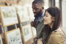 Smiling young couple looking at real estate listings at storefront — Stock Photo