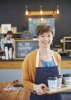 Портрет впевнена власниця жіночого кафе тримає лоток чашок кави — стокове фото