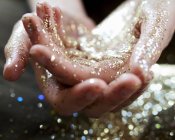Close up hands cupping gold glitter — Stock Photo