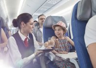 Femmina assistente di volo che serve acqua alla ragazza in aereo — Foto stock