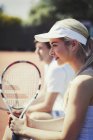 Sorrindo, jogador de tênis feminino confiante segurando raquete no campo de tênis ensolarado — Fotografia de Stock