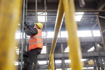 Male worker climbing ladder in factory — Stock Photo