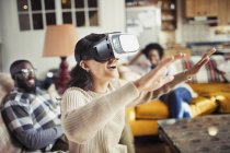 Frau gestikuliert mit Virtual-Reality-Simulator-Brille im Wohnzimmer — Stockfoto