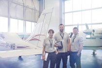 Portrait confident mechanic engineers standing in airplane hangar — Stock Photo