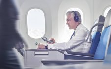 Geschäftsmann mit Kopfhörer und Fernbedienung im Flugzeug — Stockfoto