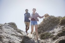 Verspieltes, energisches multiethnisches Paar läuft auf sonnigem Sommer-Sandstrand-Pfad — Stockfoto