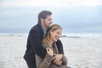 Glückliches Paar umarmt sich am Winterstrand — Stockfoto