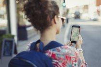 Young female tourist with backpack using GPS on smart phone on urban street — Stock Photo