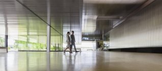 Homme d'affaires et femme d'affaires marchant dans le hall de bureau moderne — Photo de stock