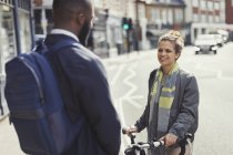 Amigos con bicicleta hablando en la soleada calle urbana - foto de stock