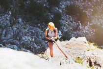 Female rock climber rappelling rock — Stock Photo