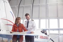 Пілот та інженер розглядають плани щодо крила літака в ангарі — стокове фото
