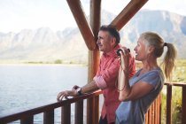 Couple with binoculars enjoying lake view from balcony — Stock Photo