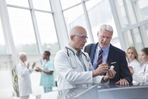 Male doctor and pharmaceutical representative discussing medication in hospital lobby — Stock Photo