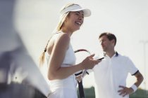 Lachende Tennisspielerin mit Handy und Tennisschläger — Stockfoto