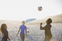 Отец и дети играют в футбол на солнечном пляже — стоковое фото