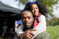 Portrait smiling father piggybacking daughter in park — Stock Photo