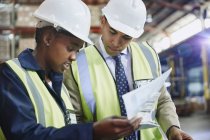 Manager und Arbeiter überprüfen Papierkram im Distributionslager — Stockfoto