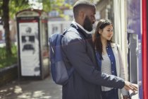 Jeune couple utilisant ATM urbain — Photo de stock