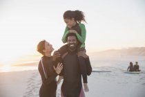 Portrait playful family surfers in wet suits on summer sunset beach — Stock Photo