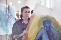 Portrait femme artiste tenant, montrant la peinture en atelier de classe d'art — Photo de stock