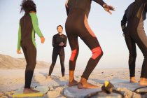 Giovane surfista che insegna surf in famiglia su tavole da surf sulla soleggiata spiaggia estiva — Foto stock