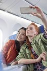Jeunes amies avec téléphone caméra posant pour selfie dans l'avion — Photo de stock