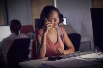 Geschäftsfrau arbeitet spät, telefoniert mit dem Smartphone am Computer im dunklen Büro — Stockfoto