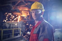 Ritratto sicuro, serio lavoratore siderurgico con walkie-talkie in acciaieria — Foto stock