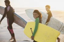 Ritratto famiglia sorridente che trasporta tavole da surf e boogie board sulla soleggiata spiaggia estiva — Foto stock