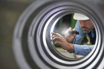 Чоловік-інженер з ліхтариком оглядає сталевий циліндр — стокове фото