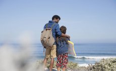 Pai e filho andando com prancha de boogie na ensolarada praia do oceano de verão — Fotografia de Stock
