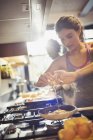 Giovane donna rompere uovo sopra padella sul fornello in cucina — Foto stock