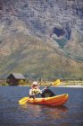 Uomo anziano attivo kayak sul soleggiato lago estivo — Foto stock