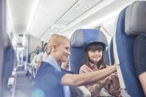Flight attendant helping girl passenger on airplane — Stock Photo