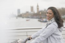 Retrato mujer sonriente bicicleta montar en el puente sobre el río Támesis, Londres, Reino Unido - foto de stock