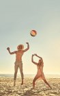 Young couple playing with beach ball on sunny summer beach — Stock Photo