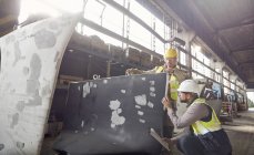 Métallurgistes examinant une pièce d'acier dans une aciérie — Photo de stock