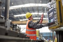 Trabajador masculino operando maquinaria en el panel de control en fábrica - foto de stock