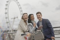 Портрет смеющихся друзей с цифровой табличкой возле Millennium Wheel, Лондон, Великобритания — стоковое фото