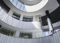 Geschäftsleute diskutieren Papierkram auf architektonischem, modernem Büro-Atrium-Balkon — Stockfoto
