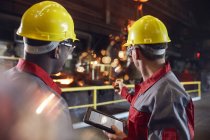 Vorgesetzter und Stahlarbeiter mit digitalem Tablet bei der Arbeit im Stahlwerk — Stockfoto