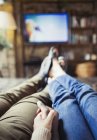 Personal perspective affectionate couple holding hands watching TV in living room — Stock Photo