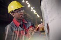 Trabalhador siderúrgico focalizado com prancheta no quadro de informações em siderurgia — Fotografia de Stock