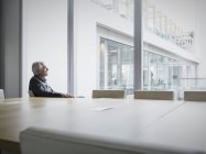 Pensive senior businessman looking out conference room window — Stock Photo