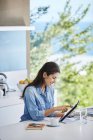 Woman working using digital tablet at kitchen counter — Stock Photo