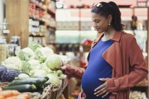 Pregnant woman shopping for cabbage in grocery store — Stock Photo