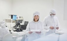 Ritratto sorridente ingegnere donna in tuta protettiva con scartoffie nel laboratorio di ricerca e test di fibra ottica — Foto stock