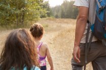 Father and daughters hiking on sunny path — Stock Photo